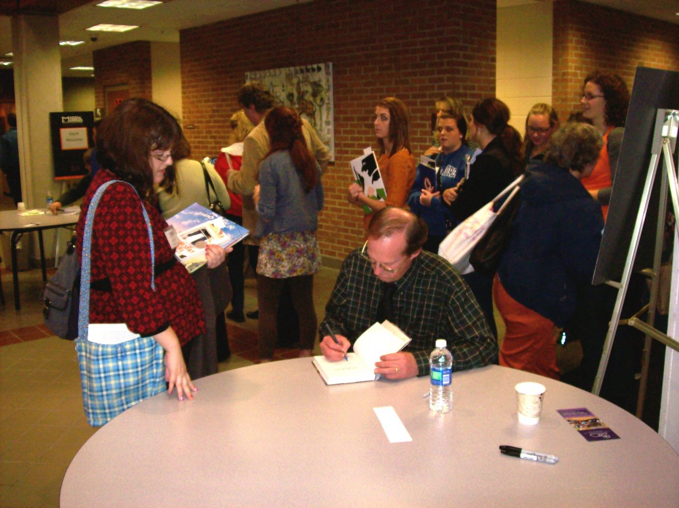 Professor and author Gary Schmidt signs a book at the Mazza conference.  Photo by Anna Lambers