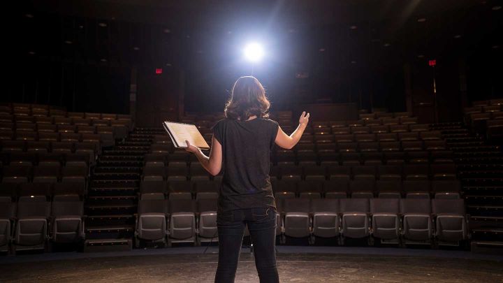 A performer stands on the Gezon Auditorium stage. 