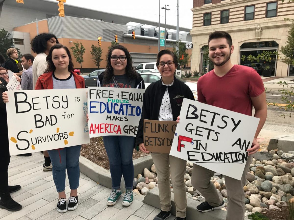 Protesters hold up signs protesting Betsy DeVos at GRRC. Photo by Isabella Ebbert.