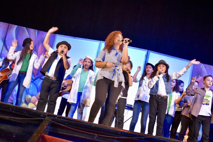 Children singing praise songs during the concert with music teacher Pauola Soto.