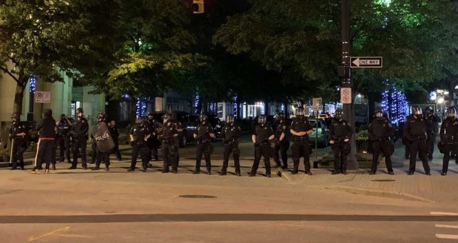 Grand Rapids police clad in riot gear defend a street entrance during a night of protests and rioting on May 30